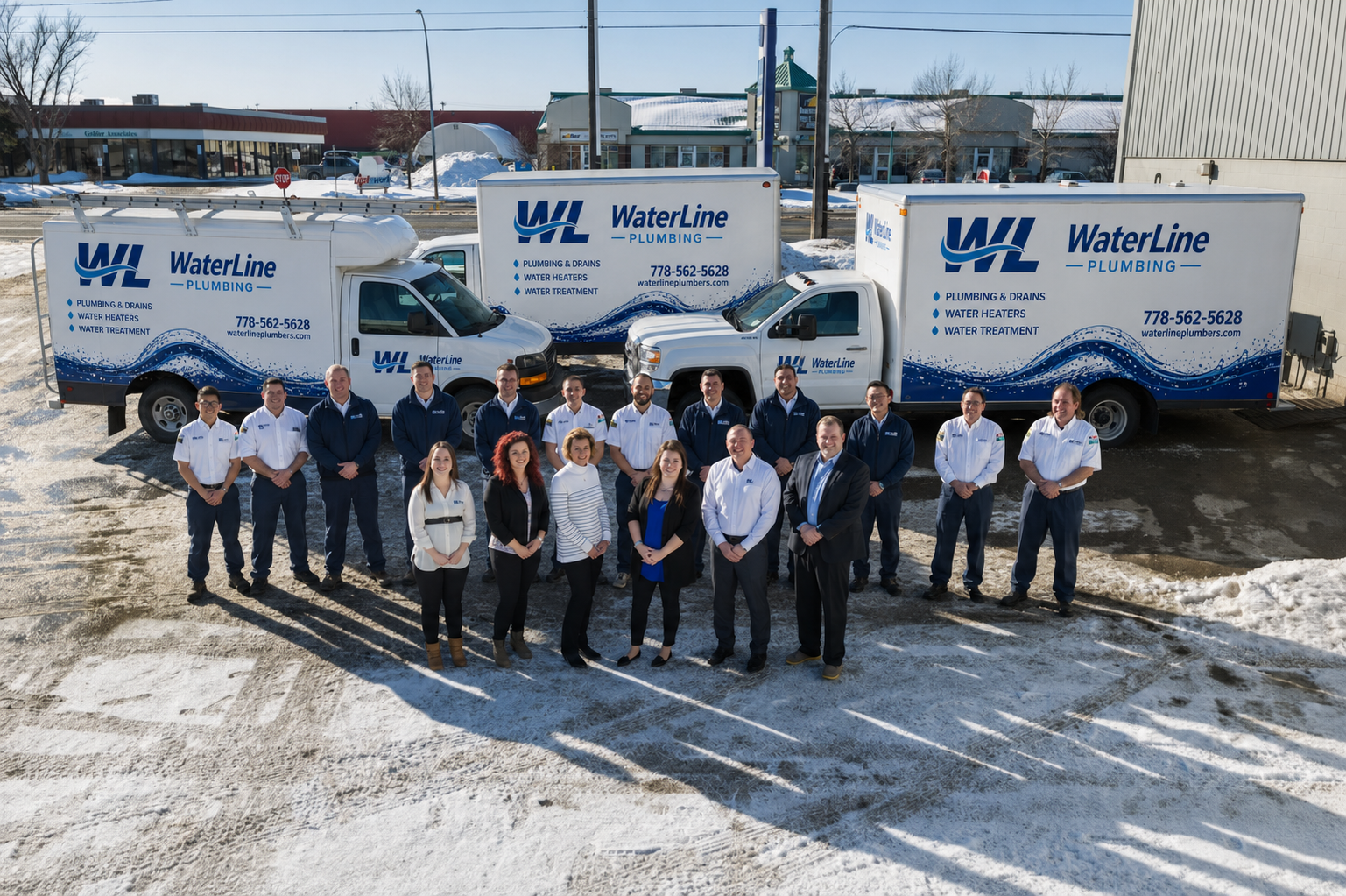 The WaterLine Plumbing team standing together in front of their branded service fleet